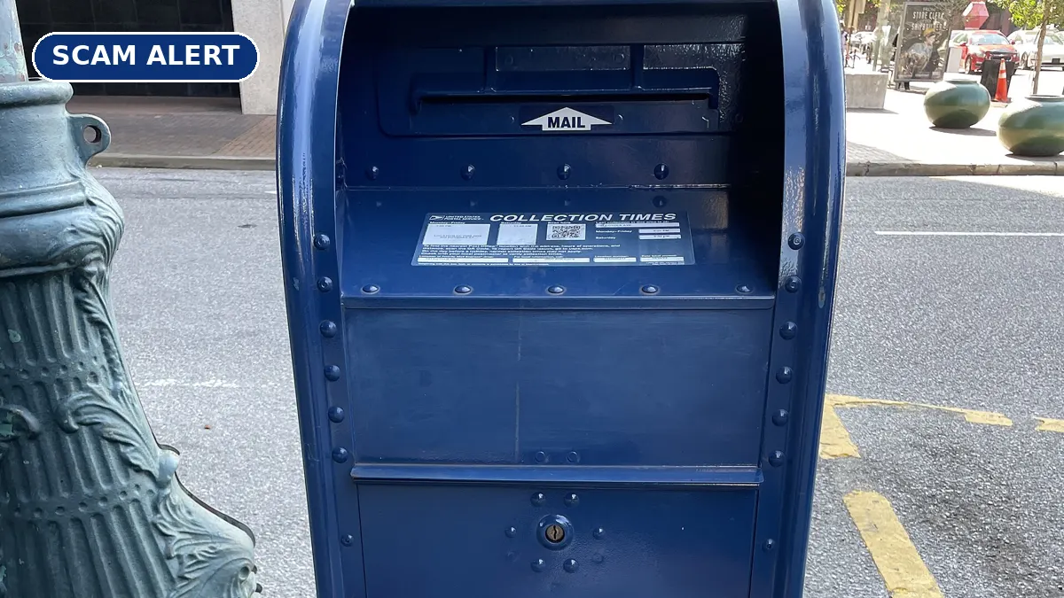 A blue USPS mail collection box on a city sidewalk